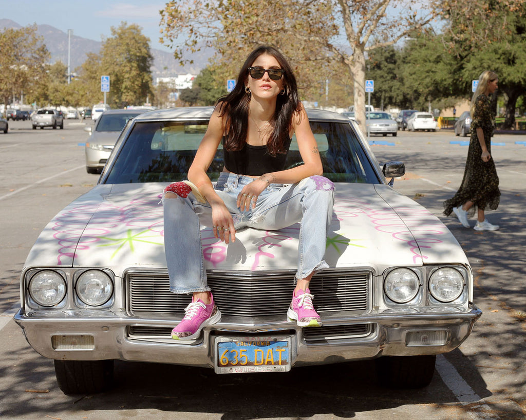 Woman sitting on a car in her pink Courser luxury sneakers