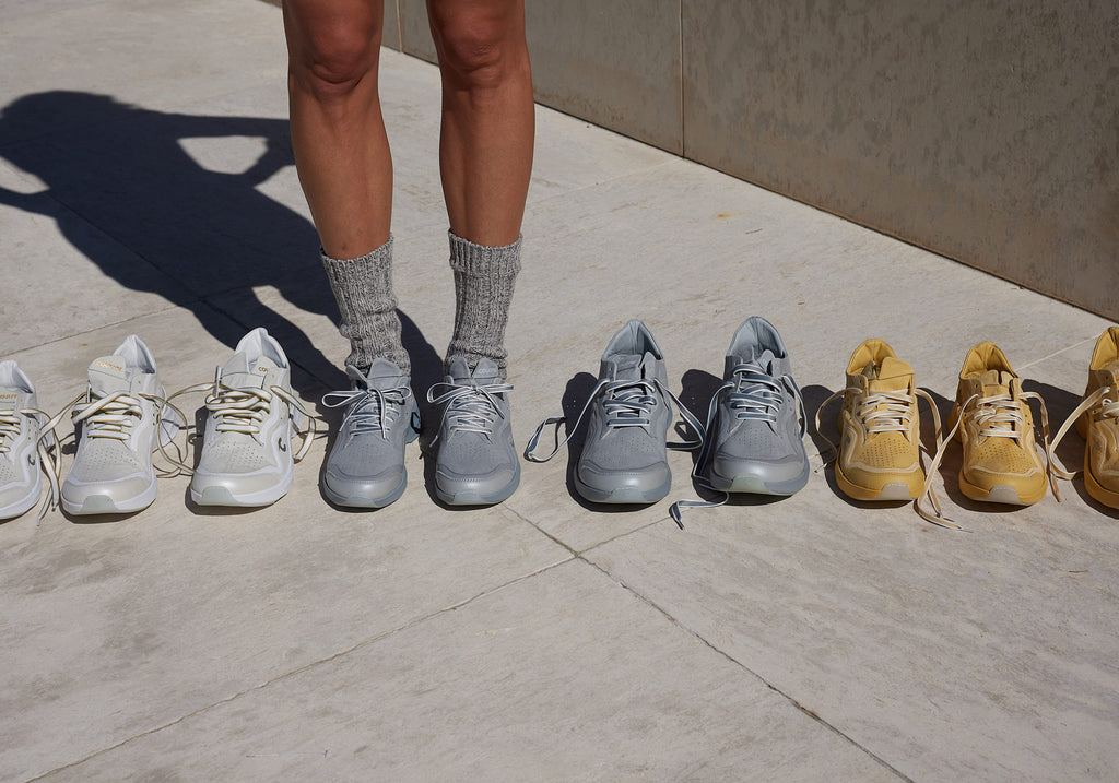 A model wearing Courser Uno sneakers with other various Courser Uno sneakers in the scene