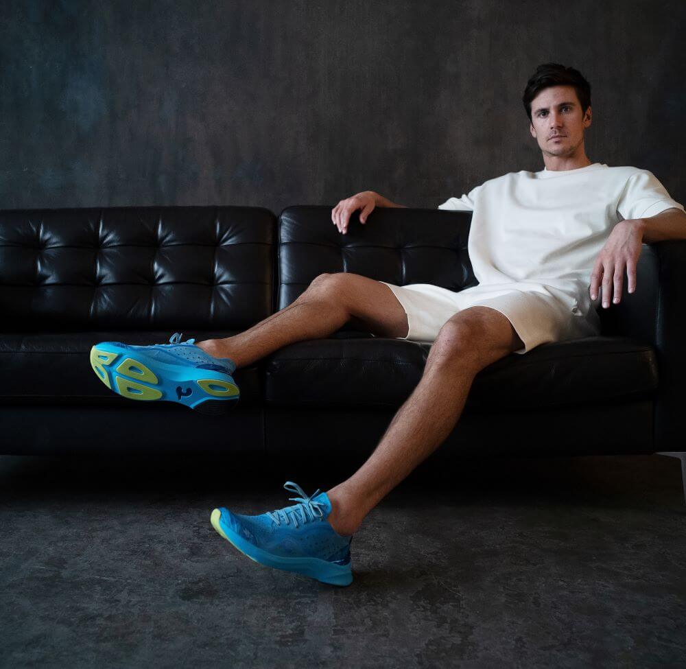 man on couch wearing Courser luxury sneakers in Cyan